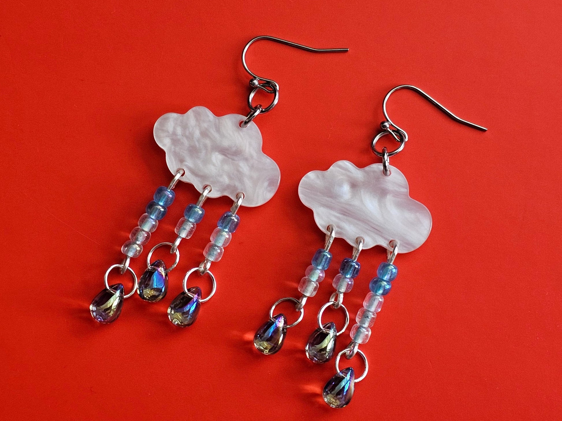 Rain cloud earrings with hypoallergenic titanium or surgical steel ear wires. Iridescent beads for water droplets. Made from stainless steel, titanium and acrylic so it is light and durable.