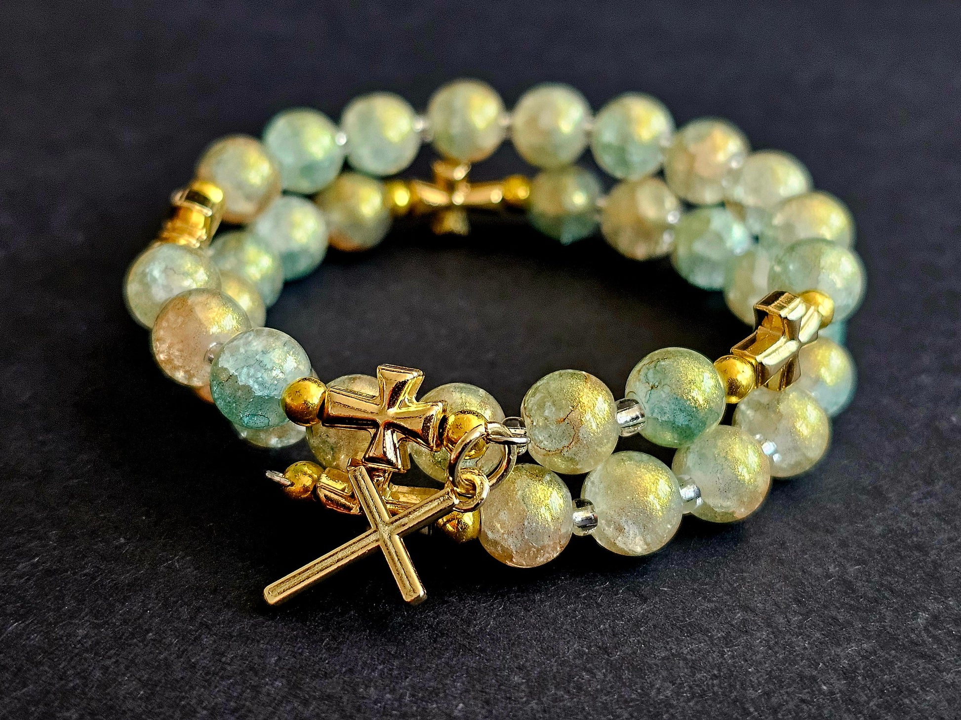 Green and gold rosary bracelet with gold cross pendant.