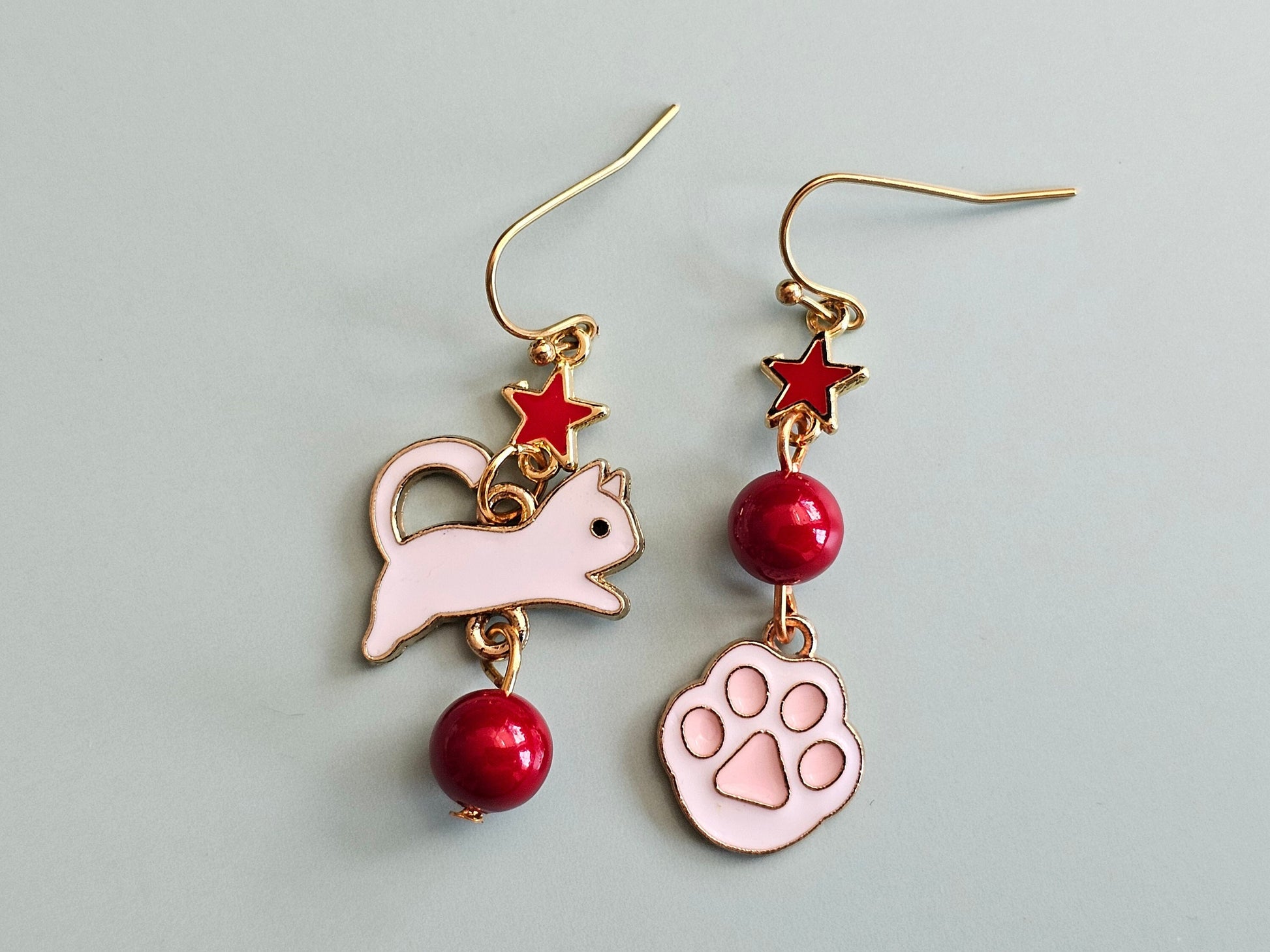 Mismatched cat and ball earrings with hypoallergenic ear wires.