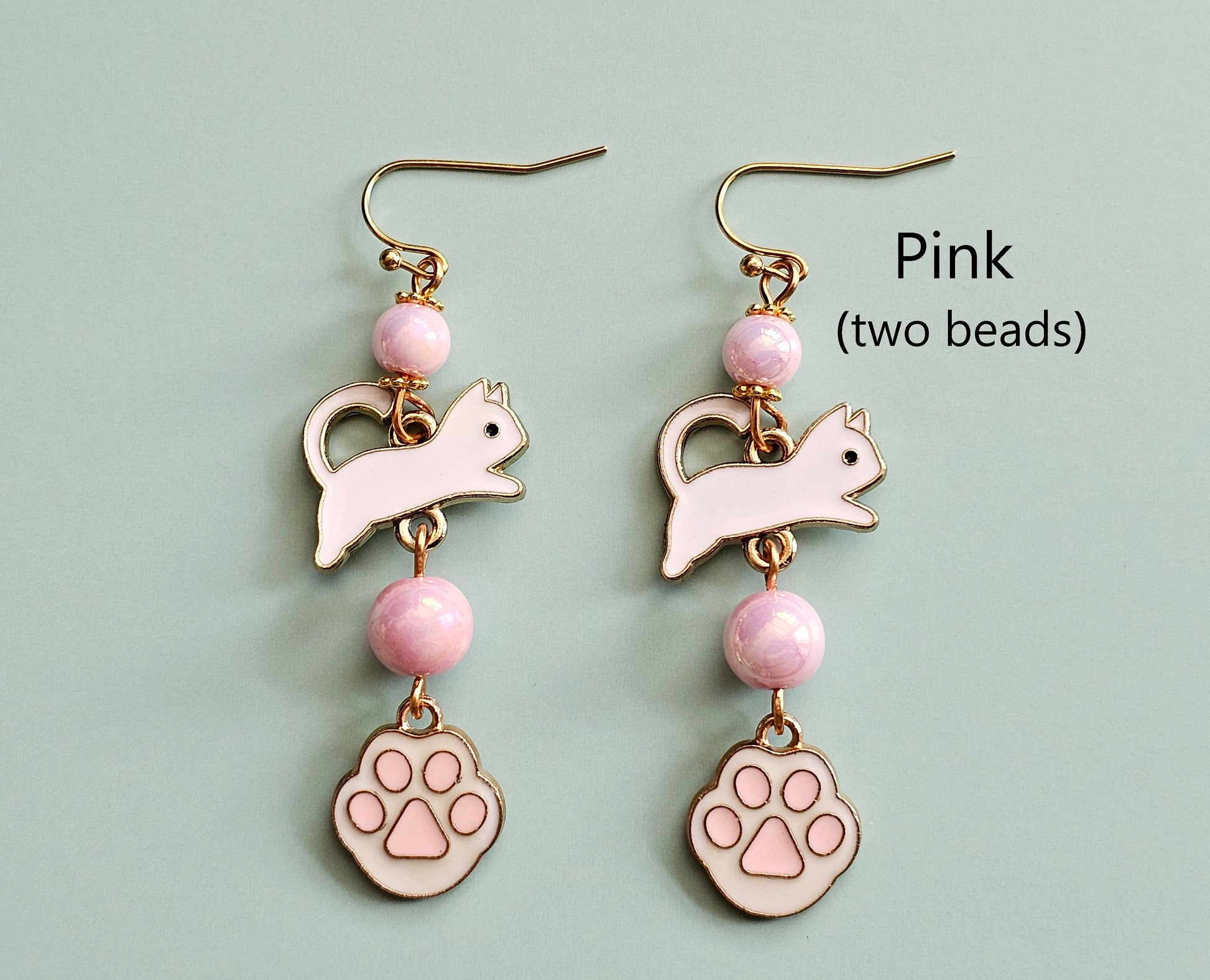 White cat earrings with paws, toe beans and pink beads.