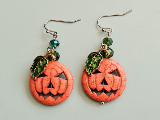 a pair of earrings with a carved pumpkin