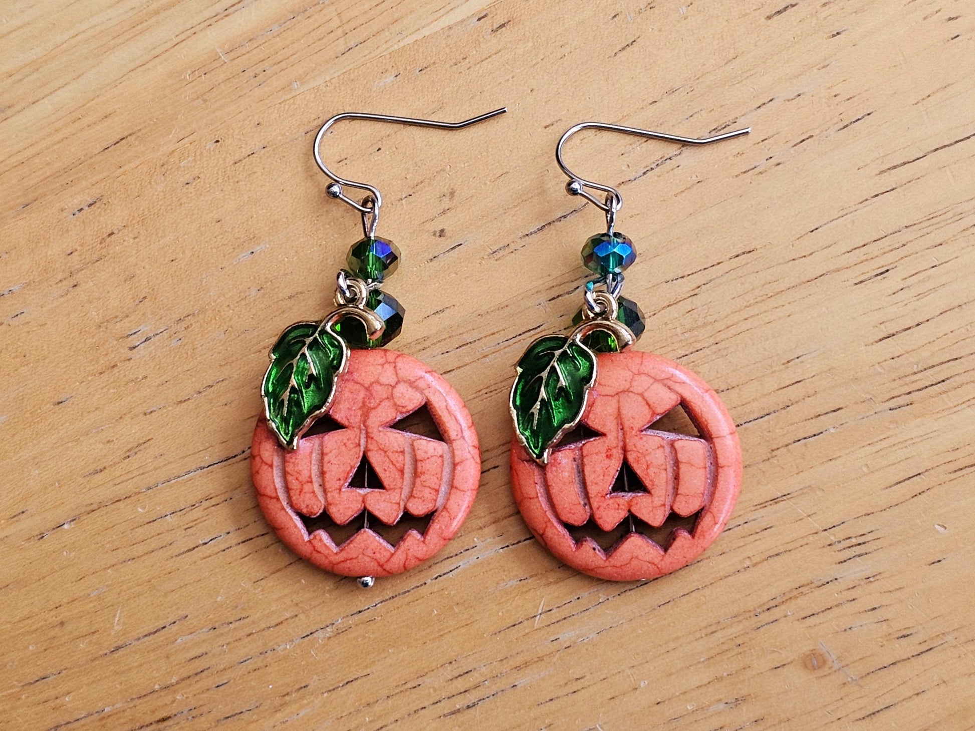 a pair of earrings with a carved pumpkin