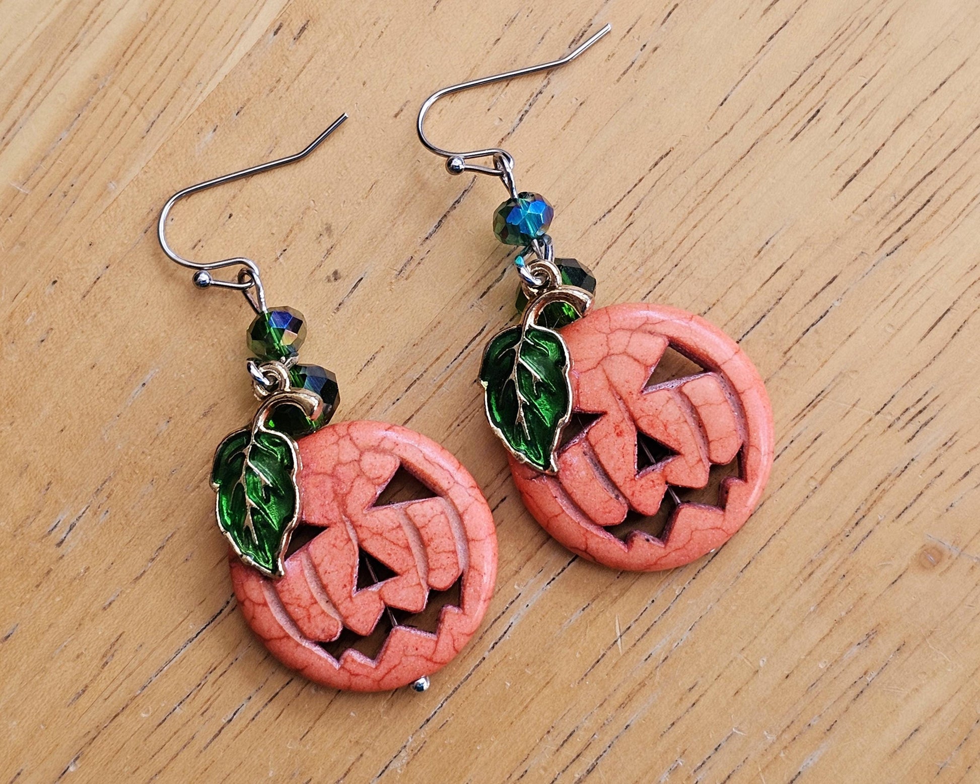 a pair of earrings with a carved pumpkin