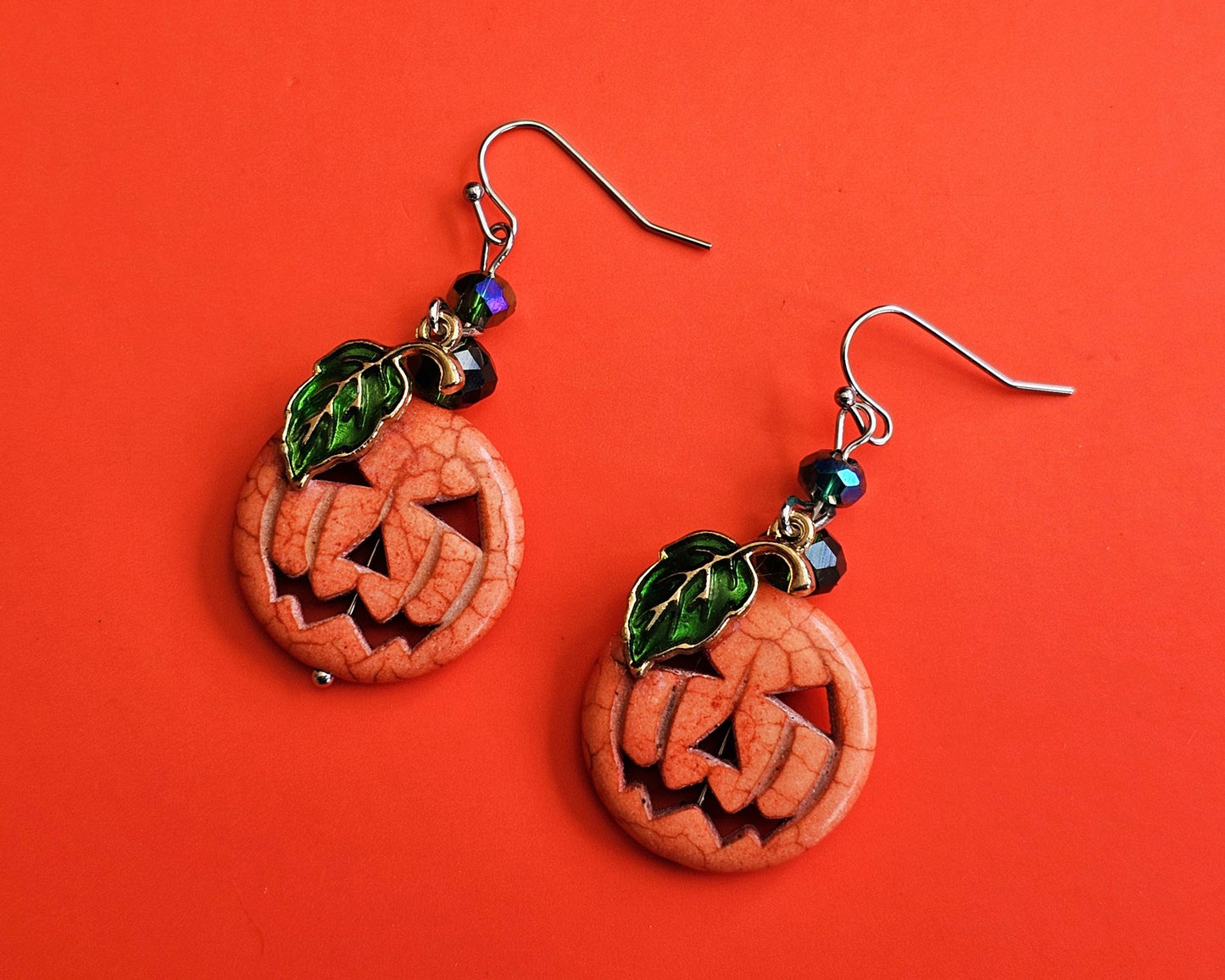 a pair of earrings with carved pumpkins on them