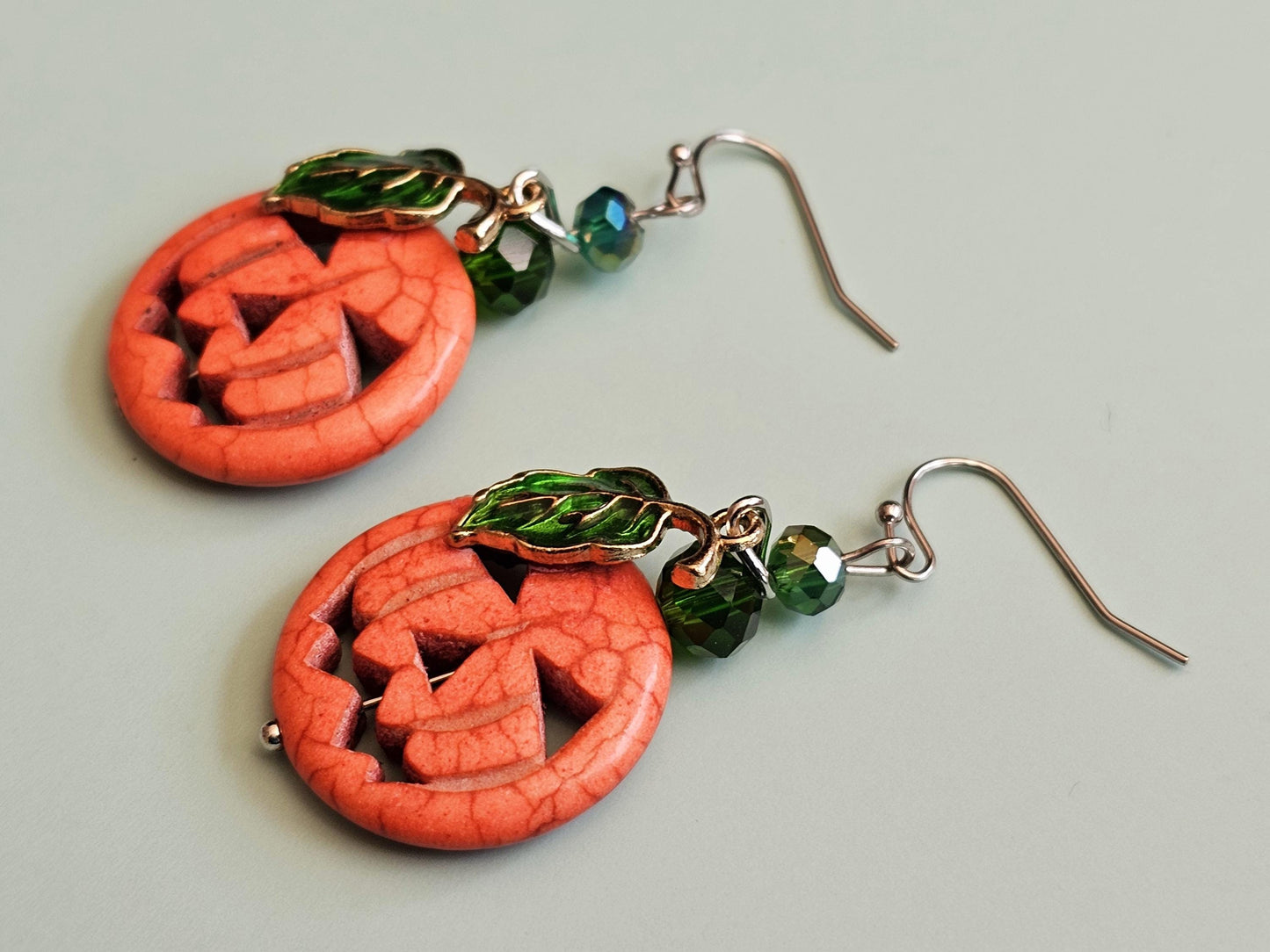 a pair of earrings with a carved jack - o - lantern design