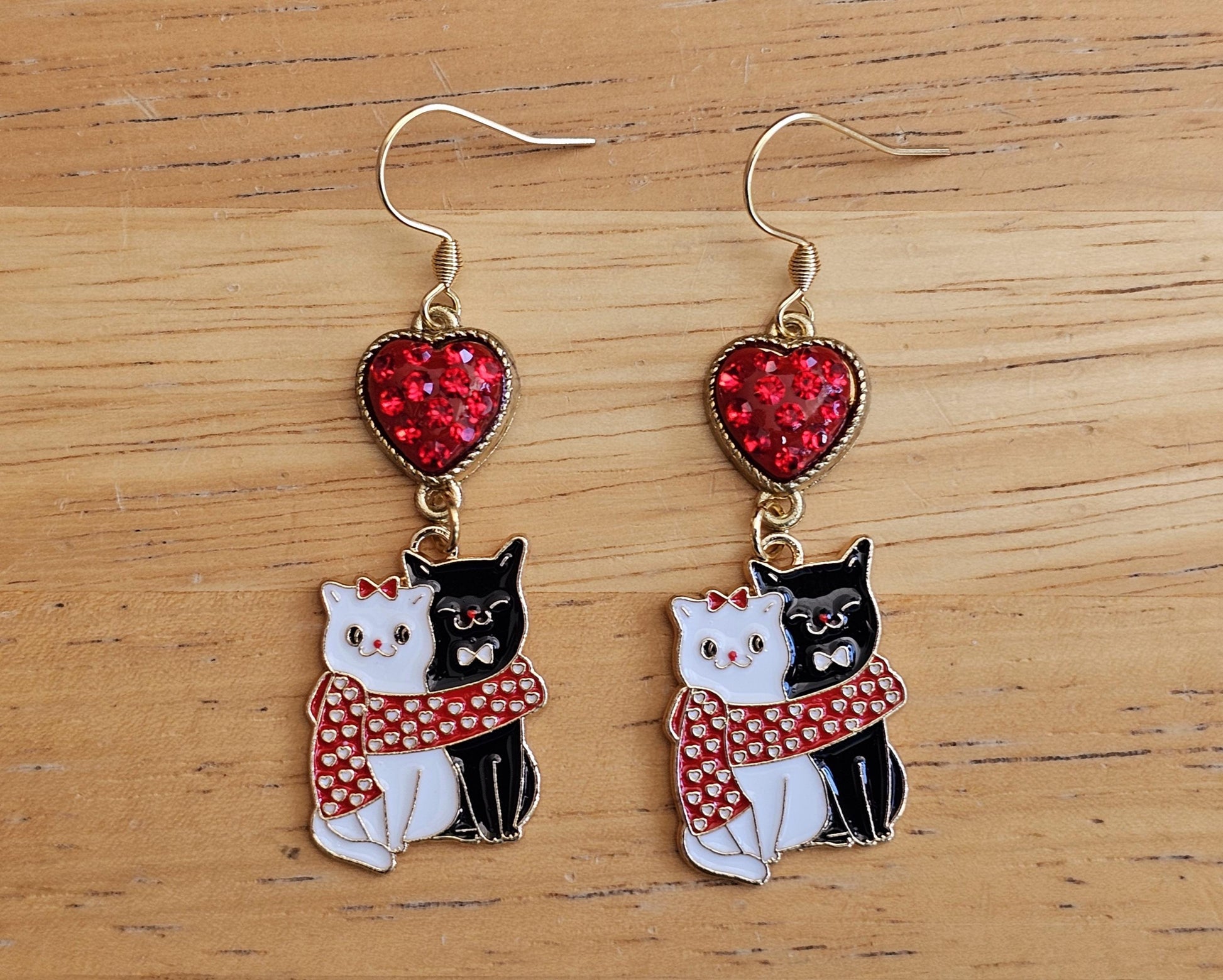 a pair of earrings with a cat and a heart