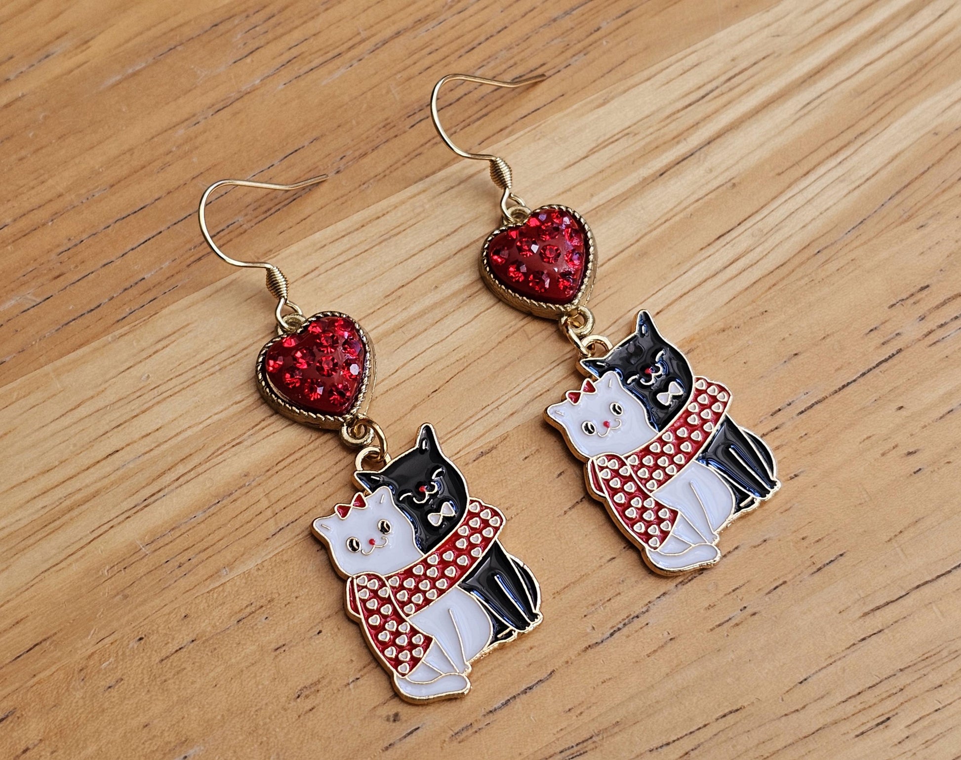 a pair of earrings featuring a cat and a heart