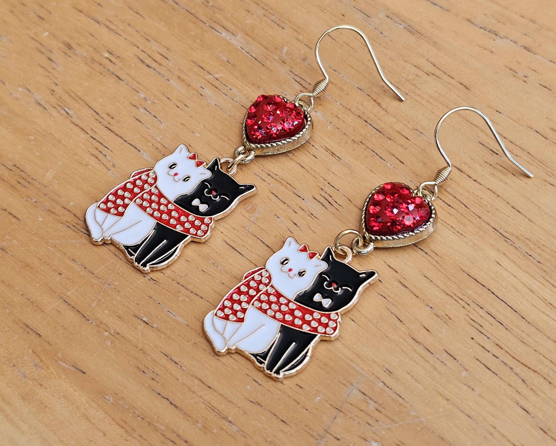 a pair of earrings with a cat and a heart