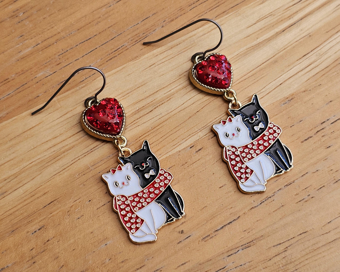 a pair of earrings with a cat and a heart