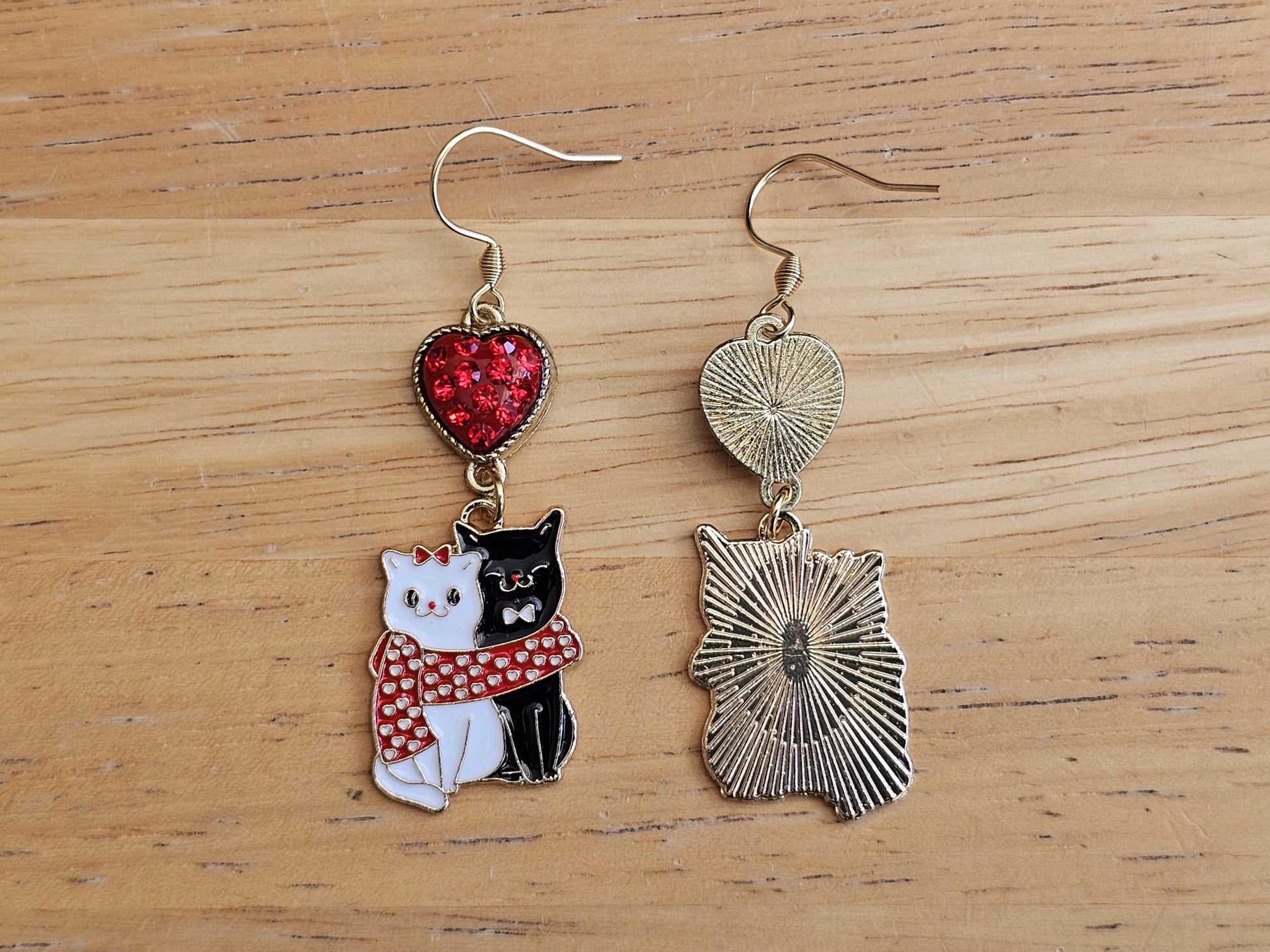 a pair of earrings featuring a cat and a heart