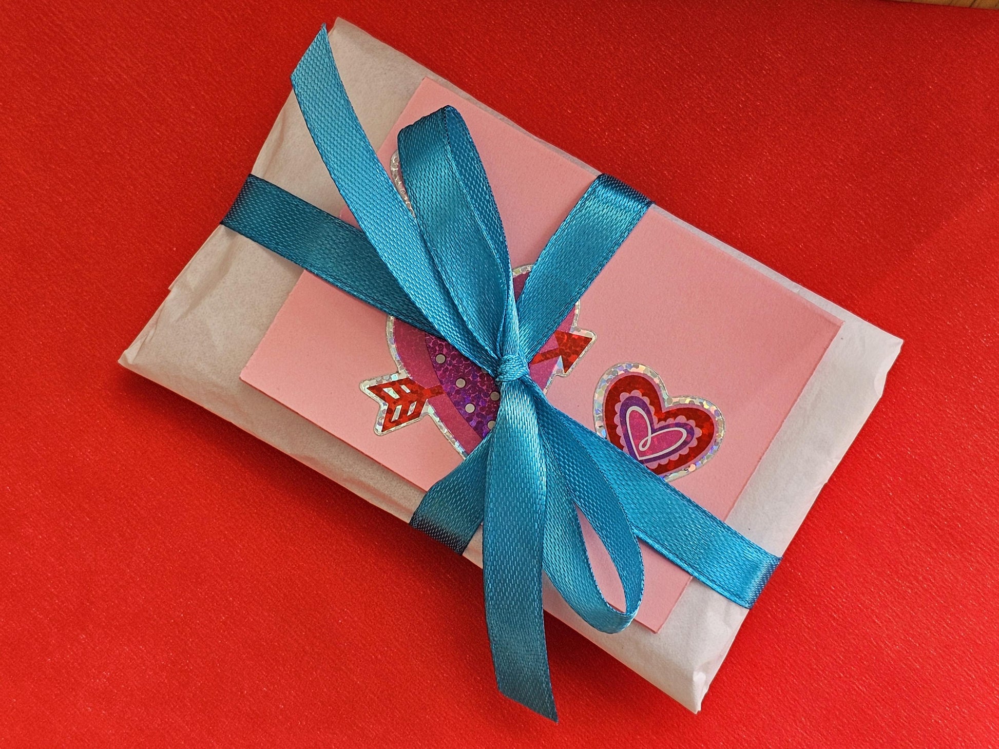 a wrapped gift with a blue ribbon on a red surface