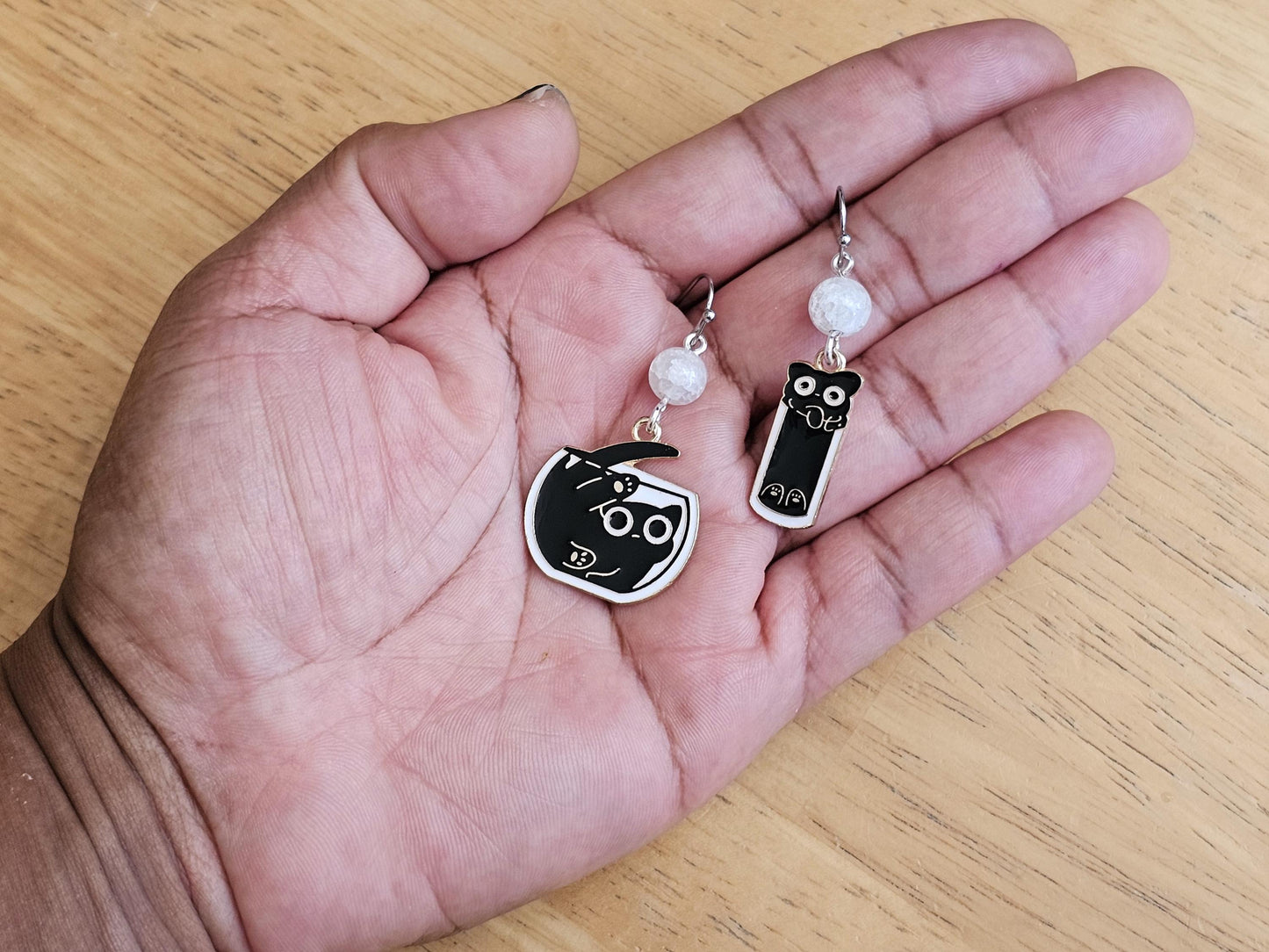 a hand holding a pair of black and white earrings