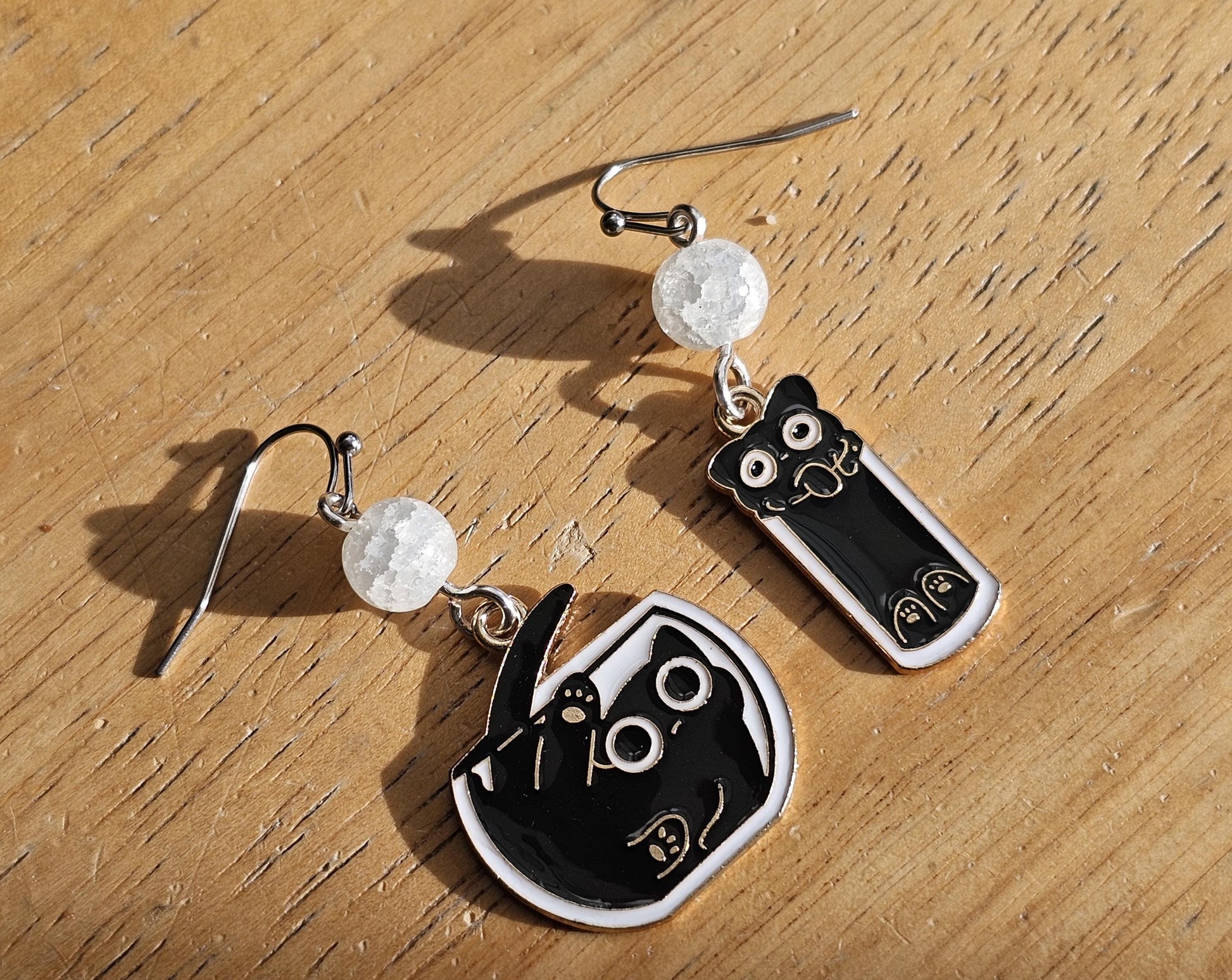 a pair of black and white earrings on a wooden table