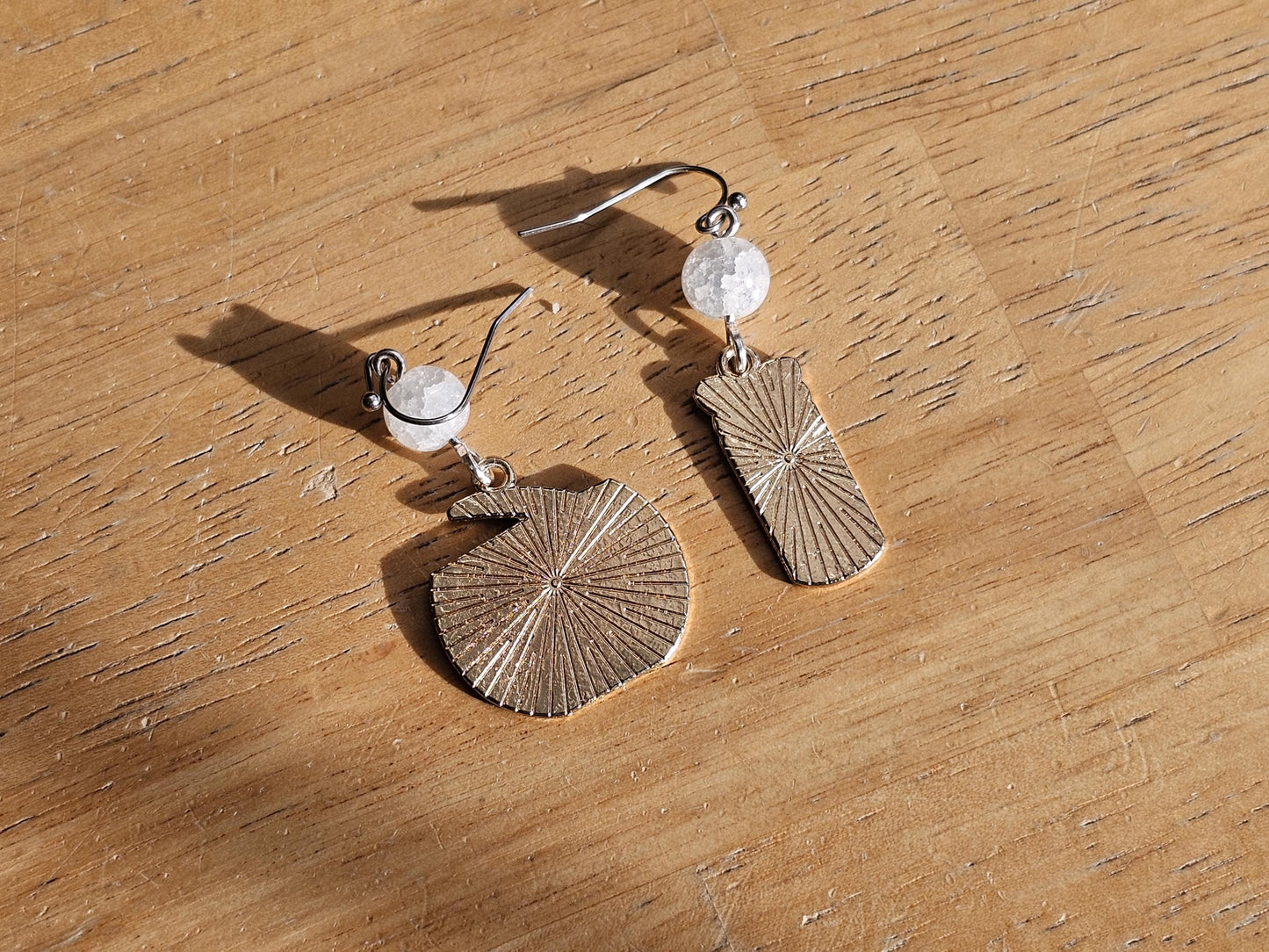 a pair of earrings sitting on top of a wooden table