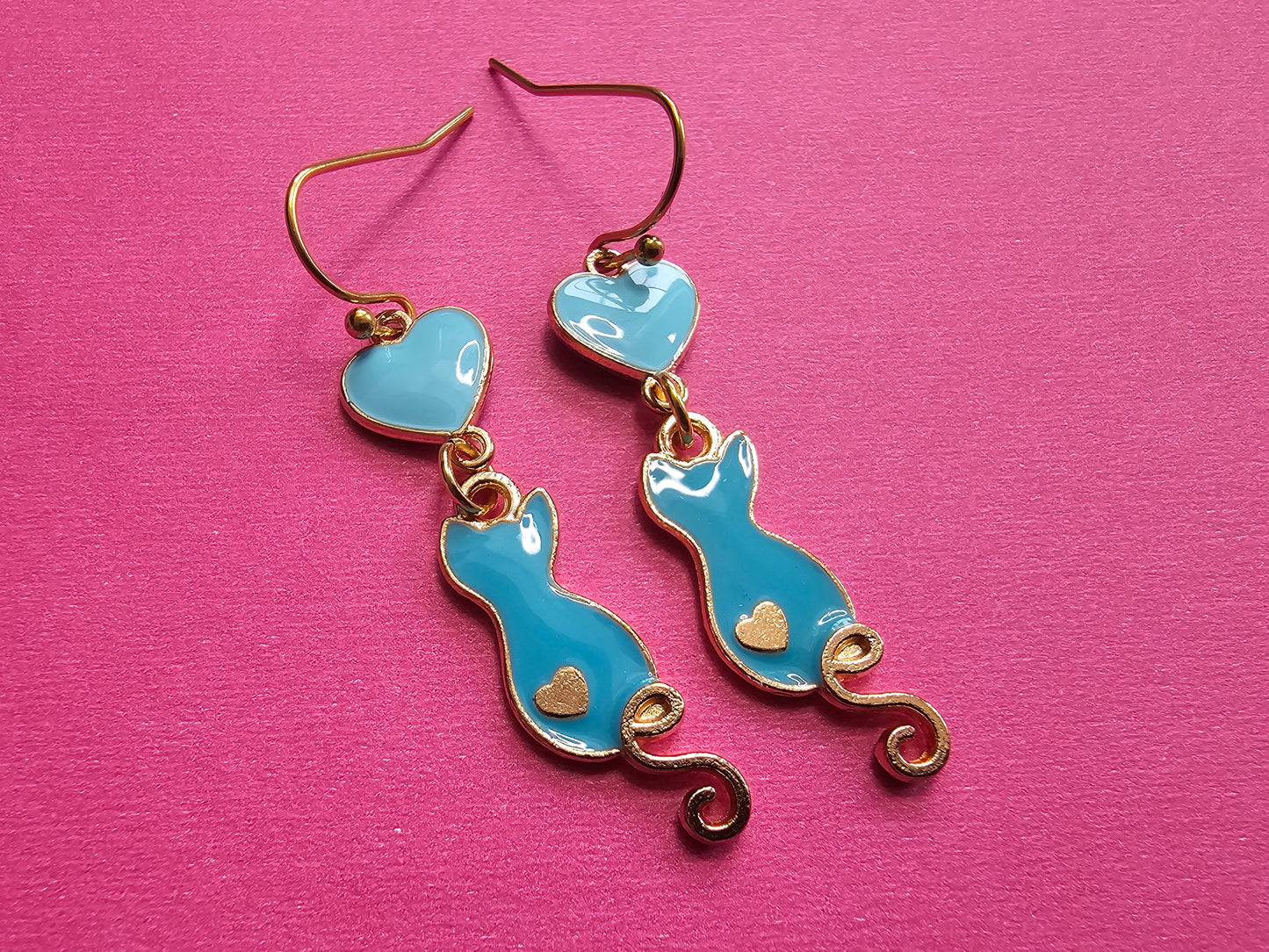 a pair of blue and gold earrings on a pink surface