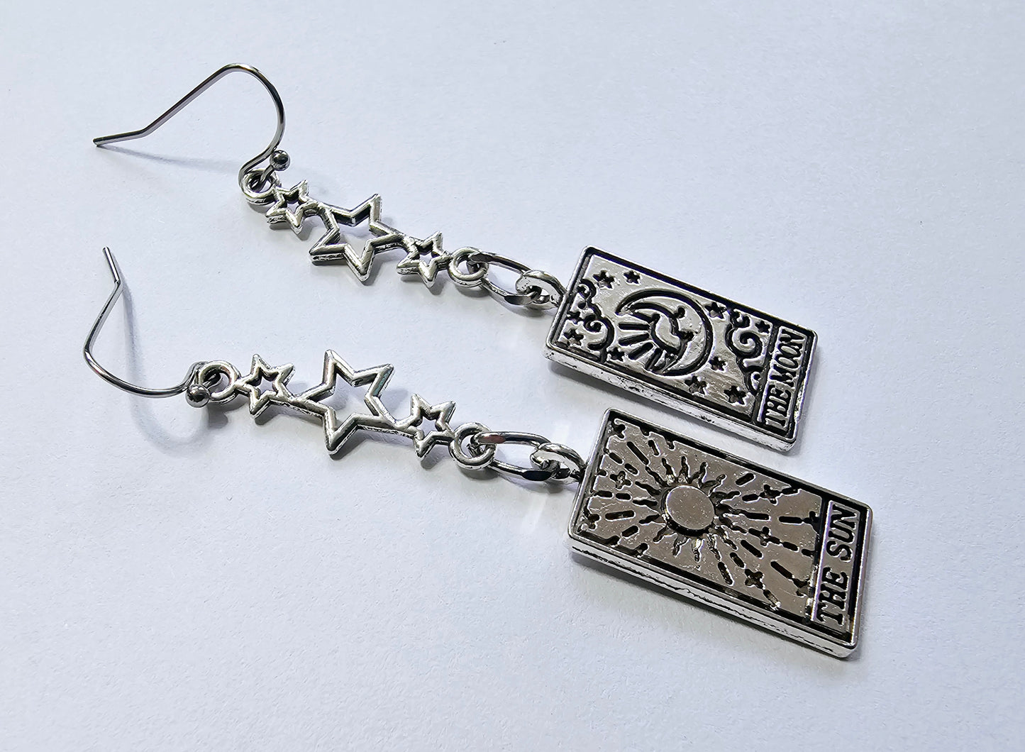 a pair of earrings with a book and stars on them