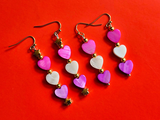 a set of five heart shaped earrings on a red background