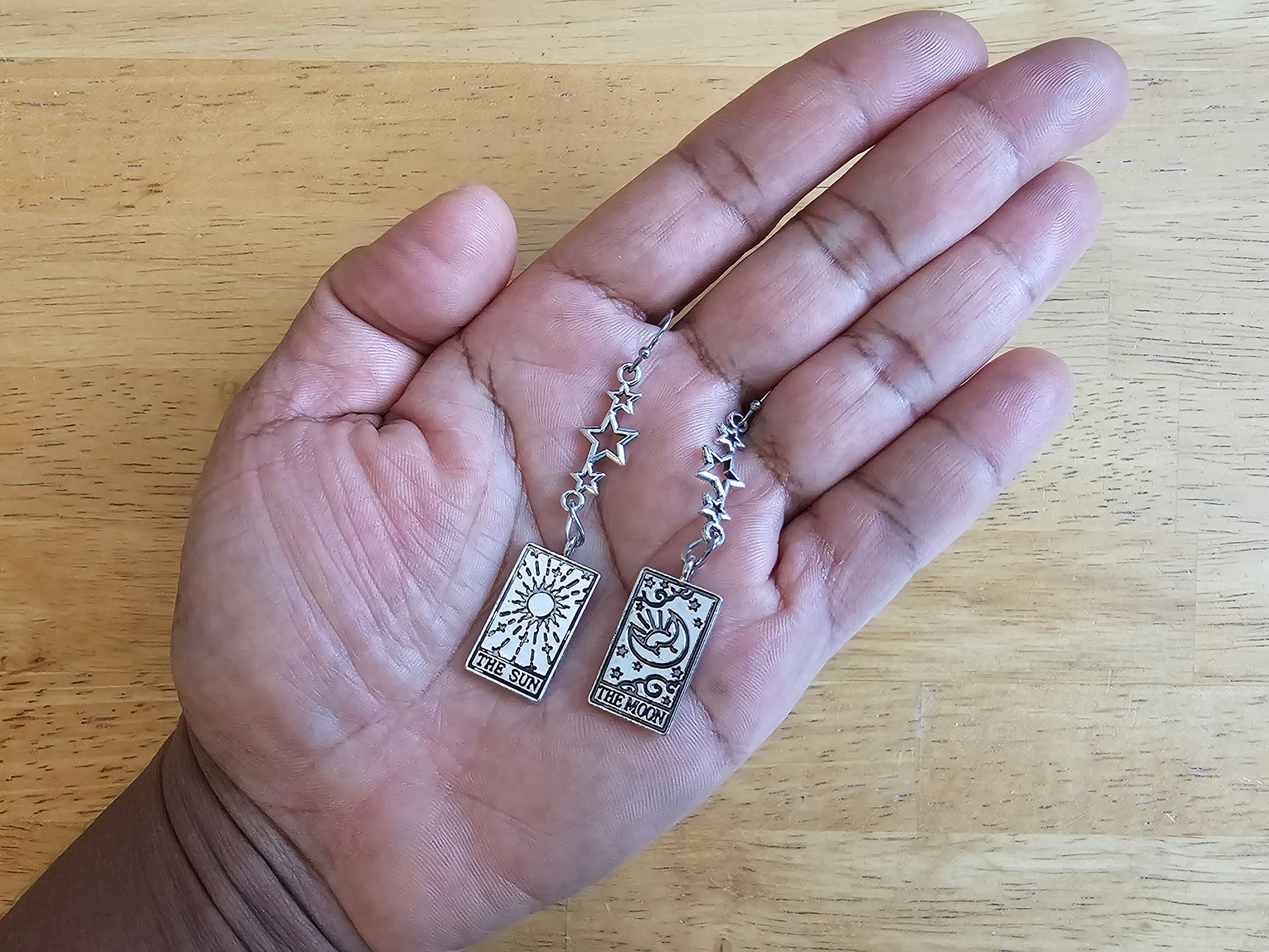 a person is holding a pair of silver necklaces