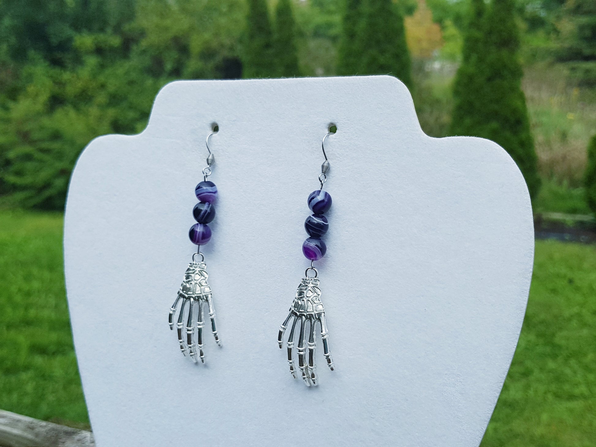 a pair of earrings with a hand holding beads