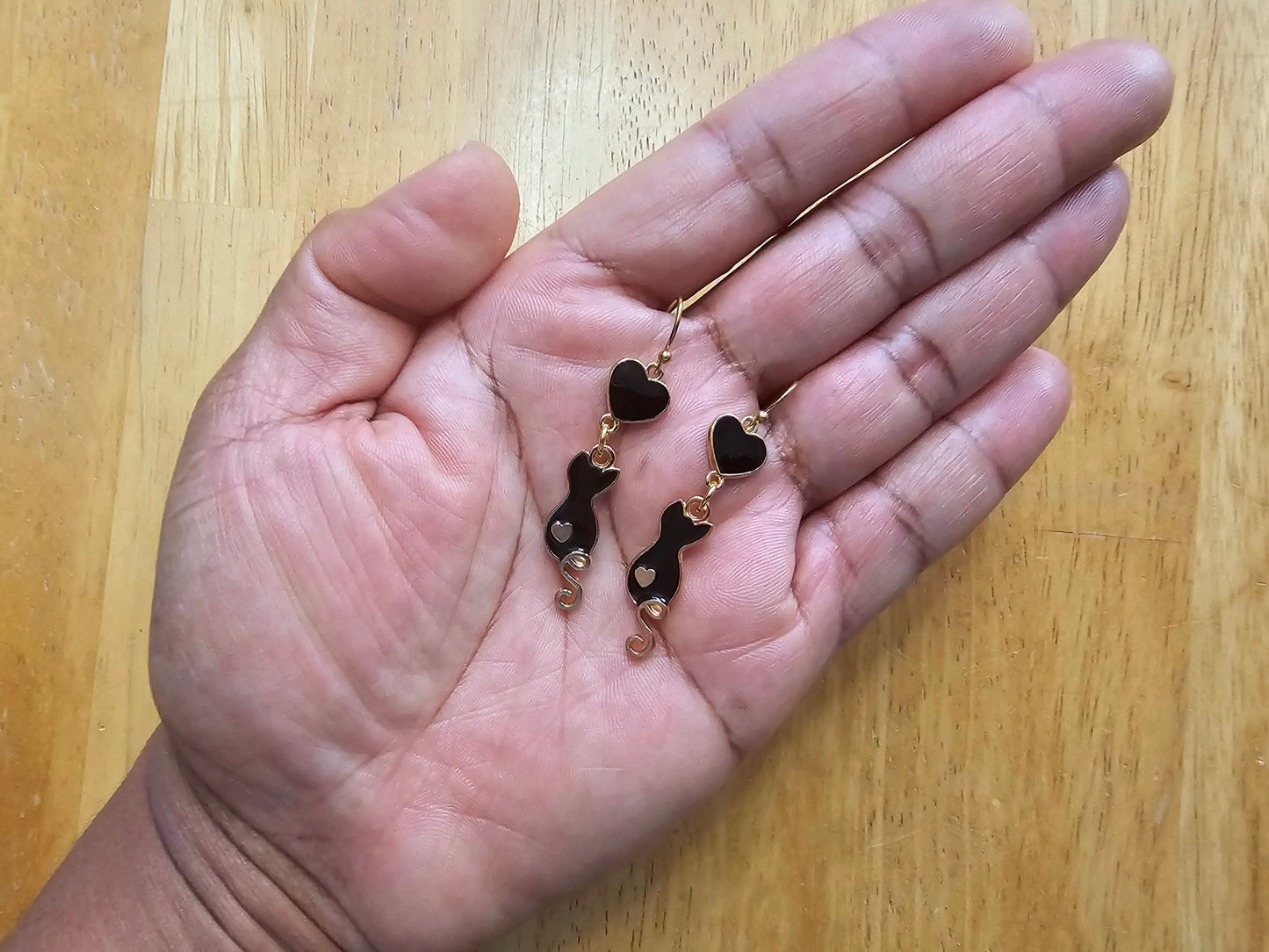 a person holding a pair of black and gold earrings