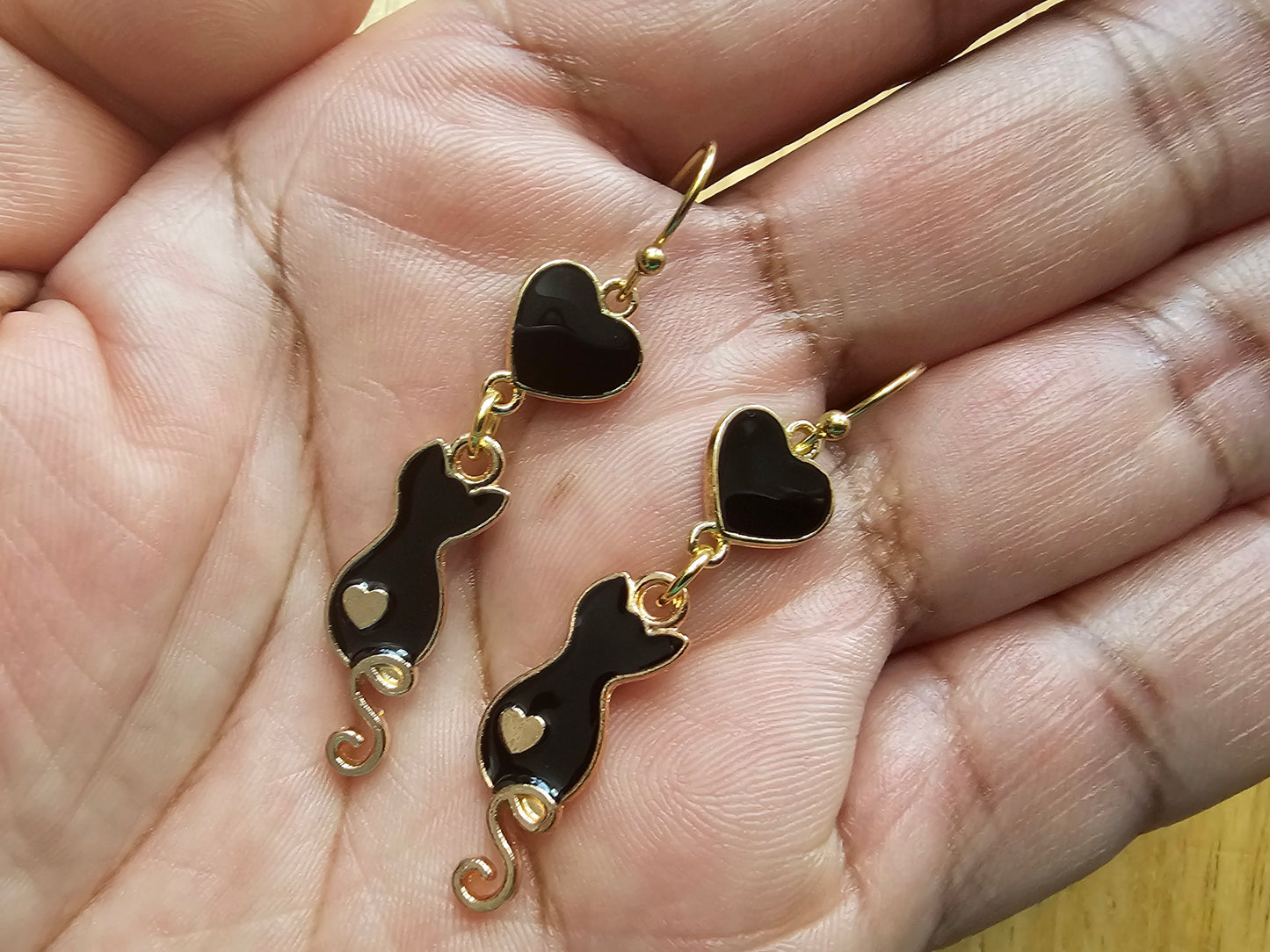 a pair of black and gold heart shaped earrings