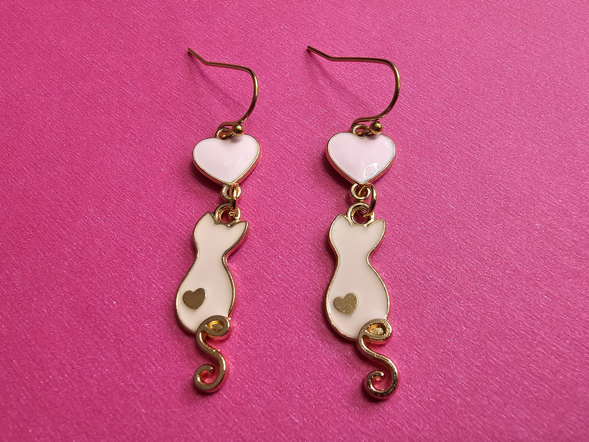 a pair of white and gold heart shaped earrings