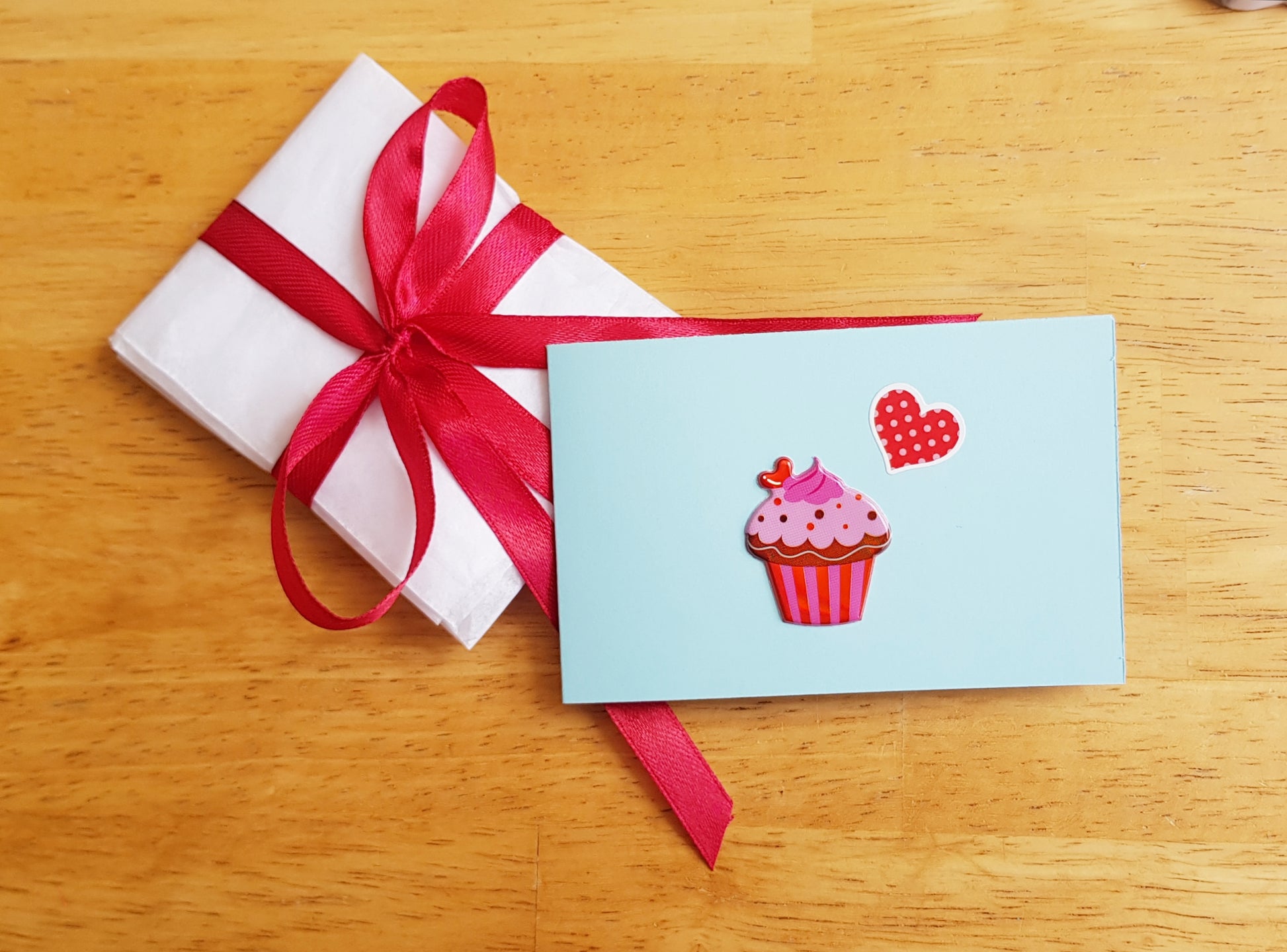 a card with a cupcake on it and a red ribbon