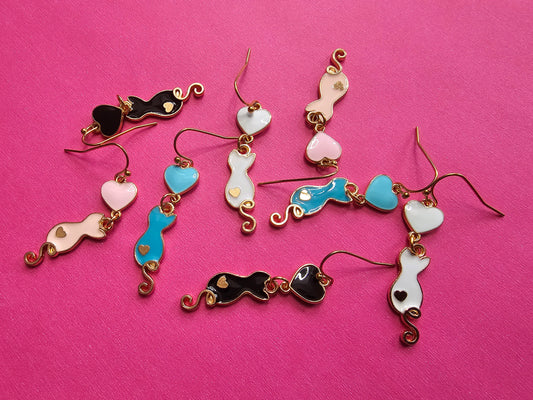 a group of different colored earrings on a pink surface